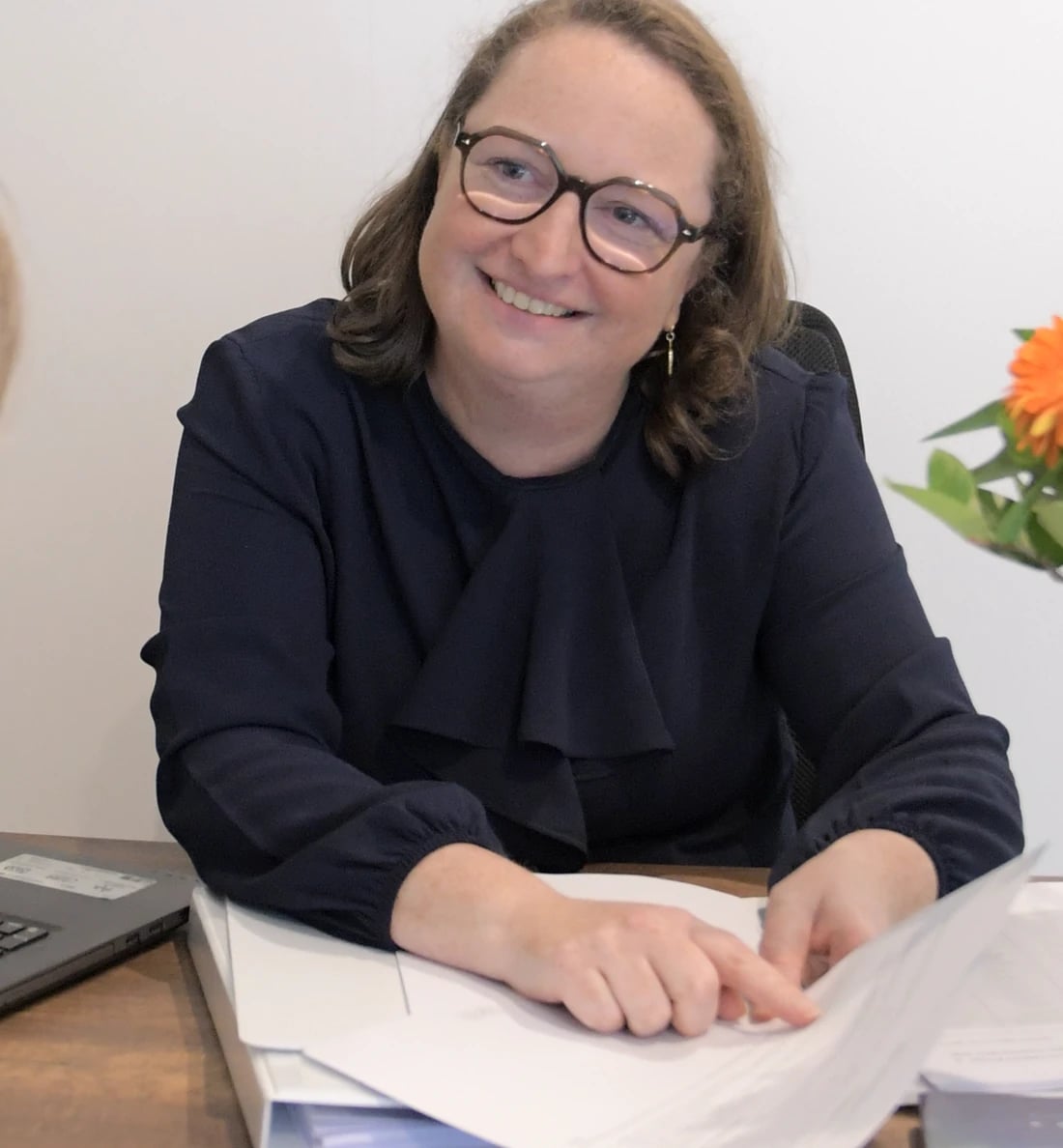 Elfriede Neels lacht aan haar bureau met een stapel documenten