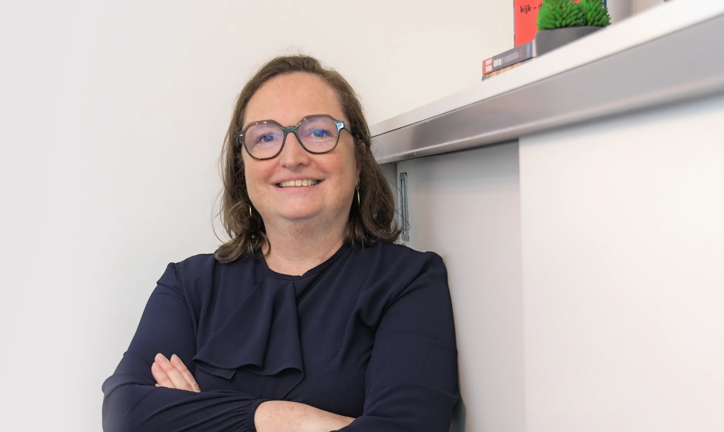 Elfriede Neels lacht met de armen gekruist in haar praktijk