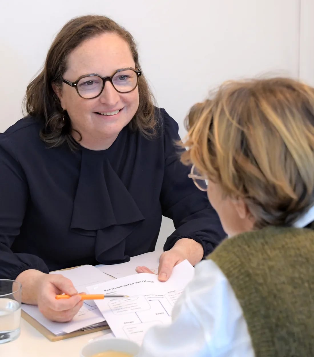 Elfriede bespreekt lachend een document met een coachee